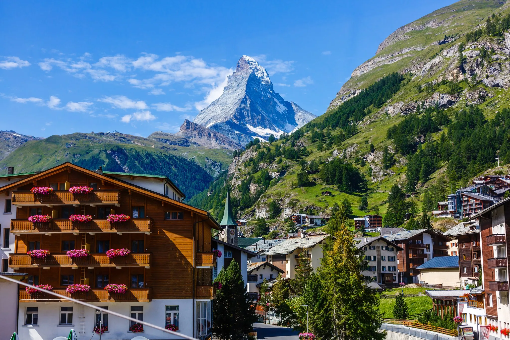 Ortsbild von Zermatt mit Holzbalkonen und Blumenkästen, dahinter die Pyramide des Matterhorns
