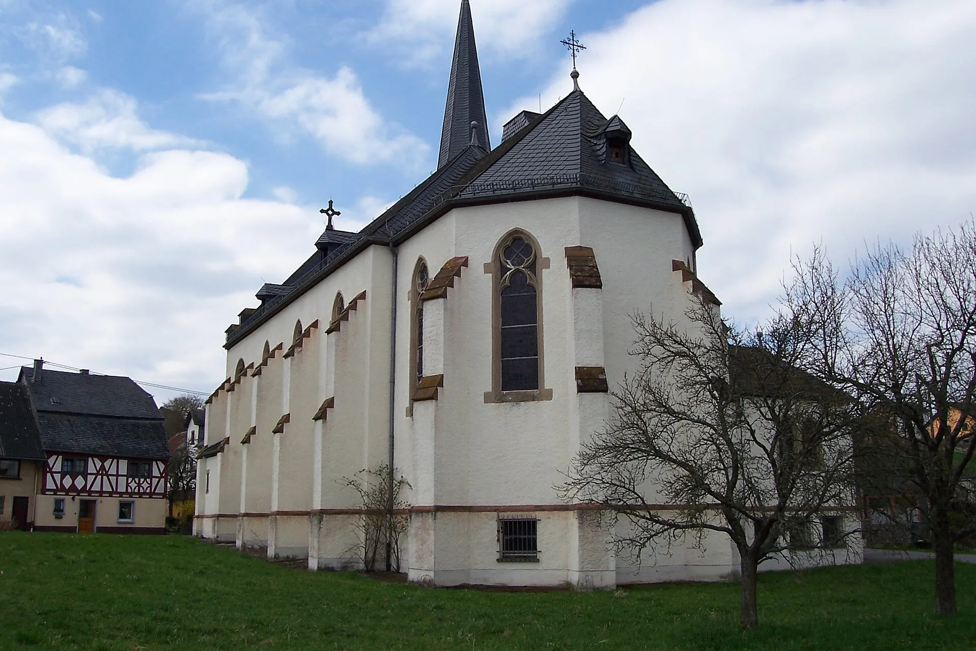 Pfarrkirche St. Quirinus in Urschmitt mit polygonalem Chor und Schieferdächern, links ein Fachwerkhaus