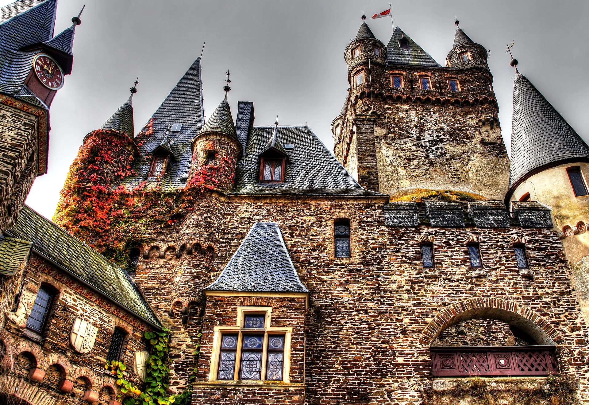 Blick aus dem unteren Burghof der Reichsburg Cochem auf Türme, Erker und rotes Laub an der Mauer